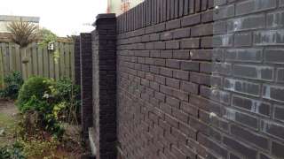 Tilburg metselen van een tuinmuur met zwarte metselstenen, de muur is enkelsteens 190cm hoog met om de 3 meter een pinant